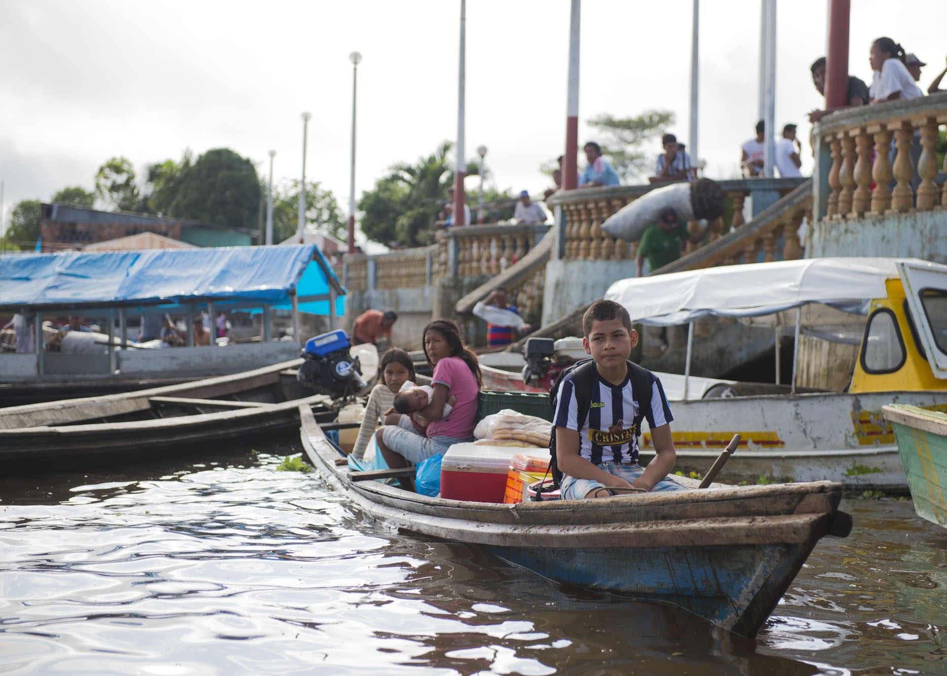 Kids sit in a boat at the dock.